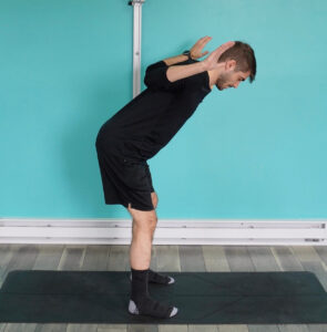 Dr. Jon S standing with knees slightly bent, hinged at the hips, opening his arms up into a W position practicing one of the best mobility exercises